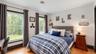 Hardwood flooring, two large windows, a tufted upholstered headboard, and recessed ceiling lighting