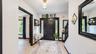 Entryway featuring a black paneled door with sidelights, wood-finish flooring, and a staircase with dark banisters