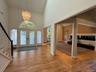 Vaulted entry with wood-finish flooring, grand chandelier, and double entry doors with arched transom