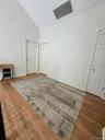 Vaulted ceiling with a ceiling vent, wood-finish flooring, and white paneled doors