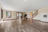 Spacious livingroom featuring wood-finish flooring, recessed lighting, and a prominent staircase with dark wood railings