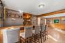 Wood-finish flooring with a built-in bar, wood paneling, and an integrated corner shelving unit
