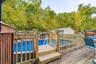 Expansive wood deck with a built-in above-ground pool, surrounded by natural rock landscaping and mature trees