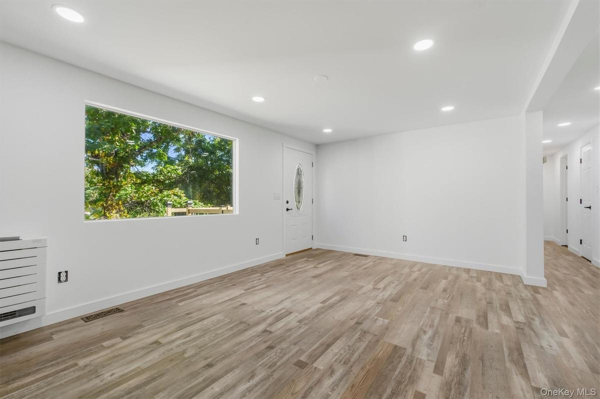 Dining Room with recessed lighting illuminates the open living area featuring wood-finish flooring, a large picture window, and a white entry door wit