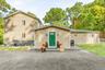 Rear view of home featuring neutral-toned siding, a vibrant green entry door, and a paved driveway