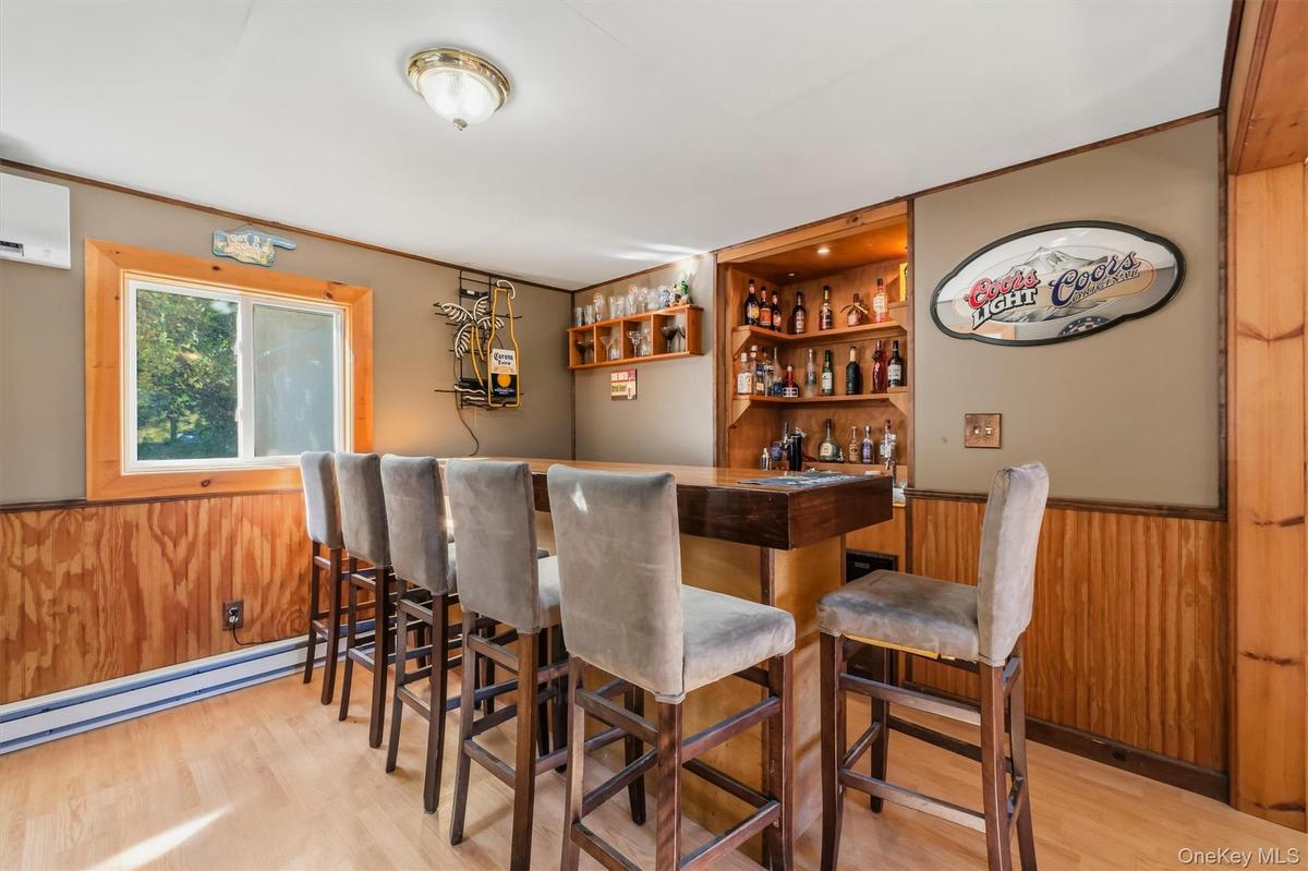 Built-in bar with wood-finish countertop, integrated shelving, and paneling accents