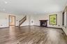 Recessed ceiling lighting, wood-finish flooring, dark wood trim, fireplace with dark wood mantel, and a staircase with wood railing