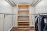 Walk-in closet featuring wood-finish flooring, built-in shelving, and multiple clothing rods