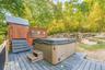 Expansive outdoor deck featuring a hot tub, a privacy screen, and a surrounding natural rock landscaping