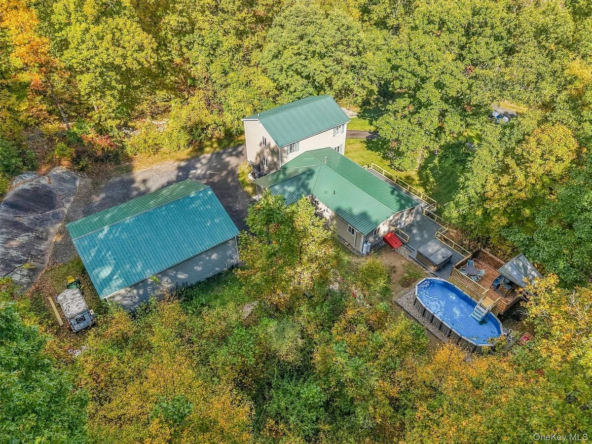 Multiple structures with green metal roofs, extensive decking, and an above-ground pool