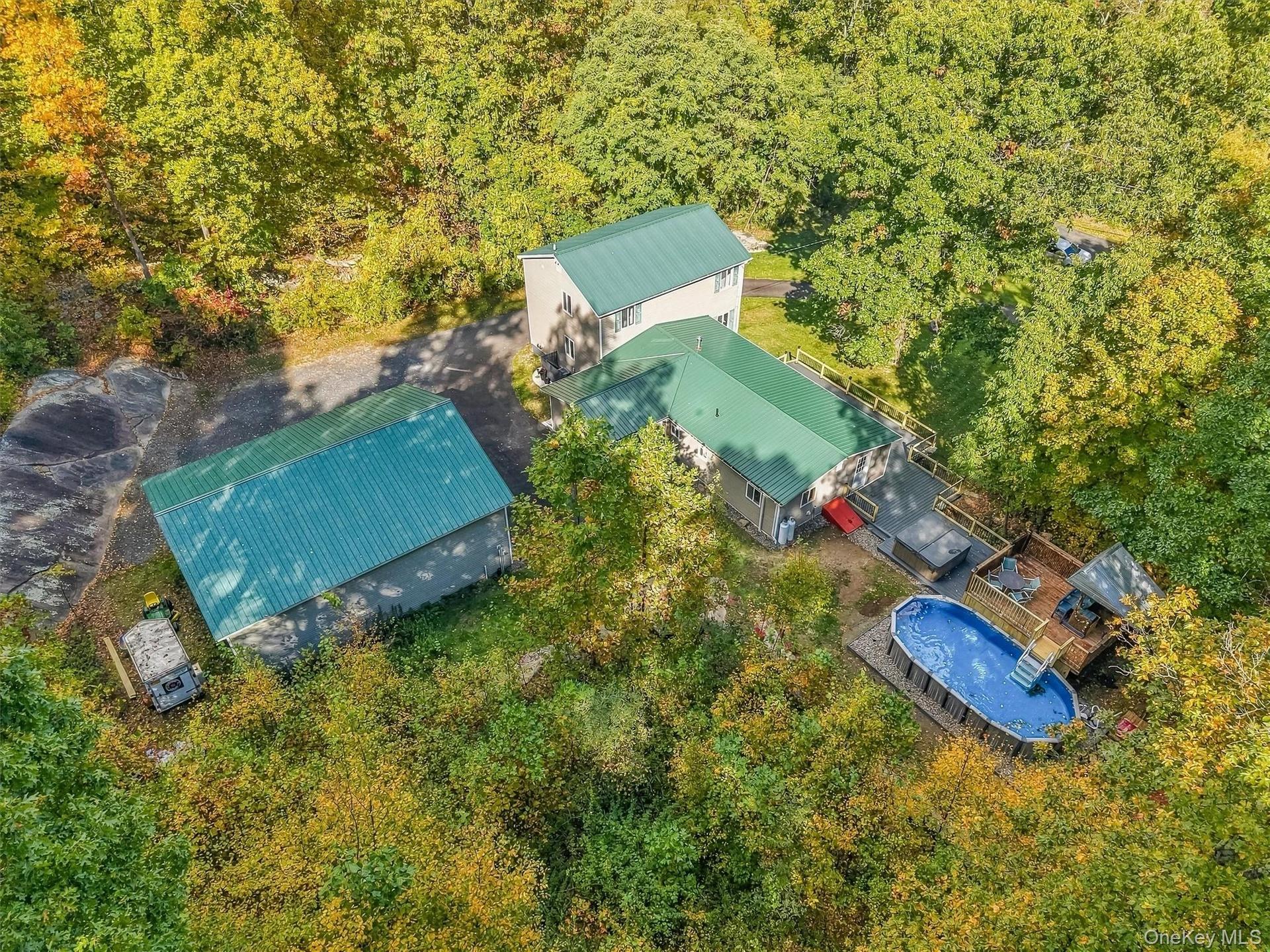 Multiple structures with green metal roofs, extensive decking, and an above-ground pool