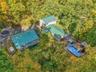 Multiple structures with green metal roofs, extensive decking, and an above-ground pool
