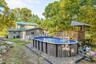 Above-ground pool with surrounding gravel, multi-level wooden deck, and elevated wooden structure