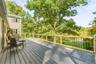 Expansive composite deck with horizontal wood-finish flooring and black metal railing system overlooking mature landscaping and open grounds