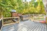 Expansive outdoor deck featuring composite decking, wood railings with black balusters, a built-in hot tub, and a multi-level play structure