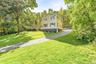 Two-story residence with siding exterior, green window shutters, and a sloped asphalt driveway