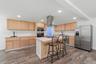 Wood-finish flooring with light wood cabinetry, a center island, stainless steel appliances, and recessed lighting