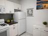 Modern kitchen featuring white cabinetry with black hardware, a dark patterned backsplash, and granite-finish countertops( virtually staged)