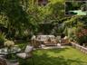 Expansive backyard featuring a lush lawn, a paved patio area, and mature perimeter trees, (virtually staged)