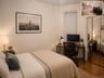 Bedroom featuring wood-finish flooring, a window with horizontal blinds, and mirrored wardrobe doors (virtually staged)
