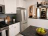 Contemporary kitchen featuring white cabinetry, dark speckled countertops, and a gray subway tile backsplash (virtually staged)