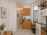 Kitchen featuring wood-finish cabinetry, white appliances, and a stainless steel sink (virtually staged)