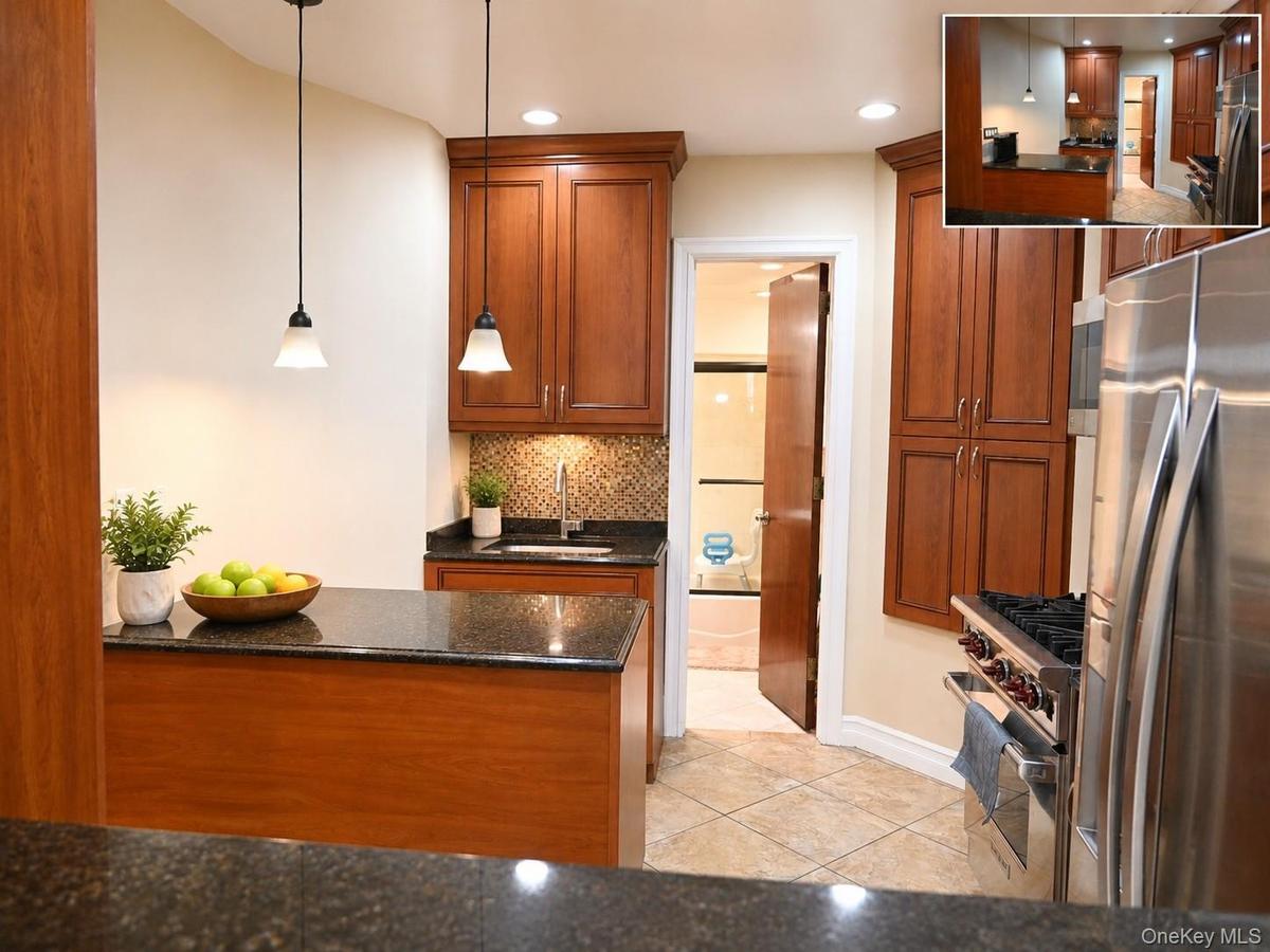 Kitchen featuring medium-tone wood cabinetry, speckled dark countertops, tile flooring, stainless steel appliances, and pendant lighting