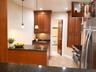 Kitchen featuring medium-tone wood cabinetry, speckled dark countertops, tile flooring, stainless steel appliances, and pendant lighting