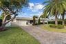 Elegant single-story residence featuring a stone and stucco exterior, wide circular driveway with paver construction, mature landscaping including a s