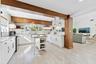 Contemporary kitchen and open-concept living space featuring white cabinetry with hardware accents, a large center island with open shelving, and stai