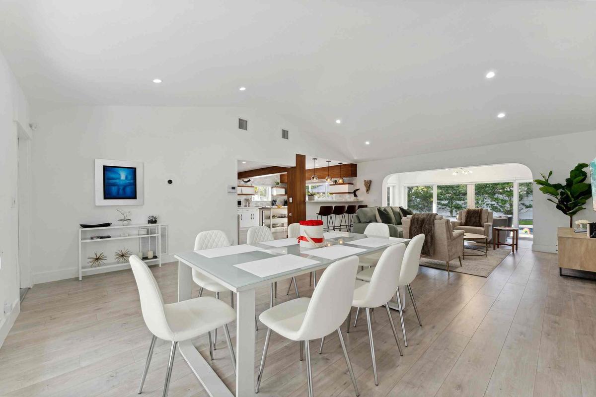 Open-concept living space featuring a wood-finish plank floor throughout, recessed ceiling lighting, and seamless integration of dining and kitchen ar