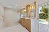 Spa-inspired primary bathroom featuring a spacious walk-in shower with white subway tile surround and pebble stone flooring, custom wood-finish vanity