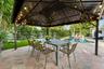 Sophisticated outdoor entertaining space featuring a sturdy metal pergola with integrated overhead lighting and ceiling fans, anchored by a spacious d