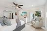 Spacious primary bedroom suite featuring a gray upholstered bed frame, ceiling fan with integrated lighting, ensuite bathroom access, and a comfortabl