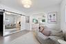 Open-concept interior featuring light wood-finish flooring, a contemporary ceiling light fixture, and an arched entryway