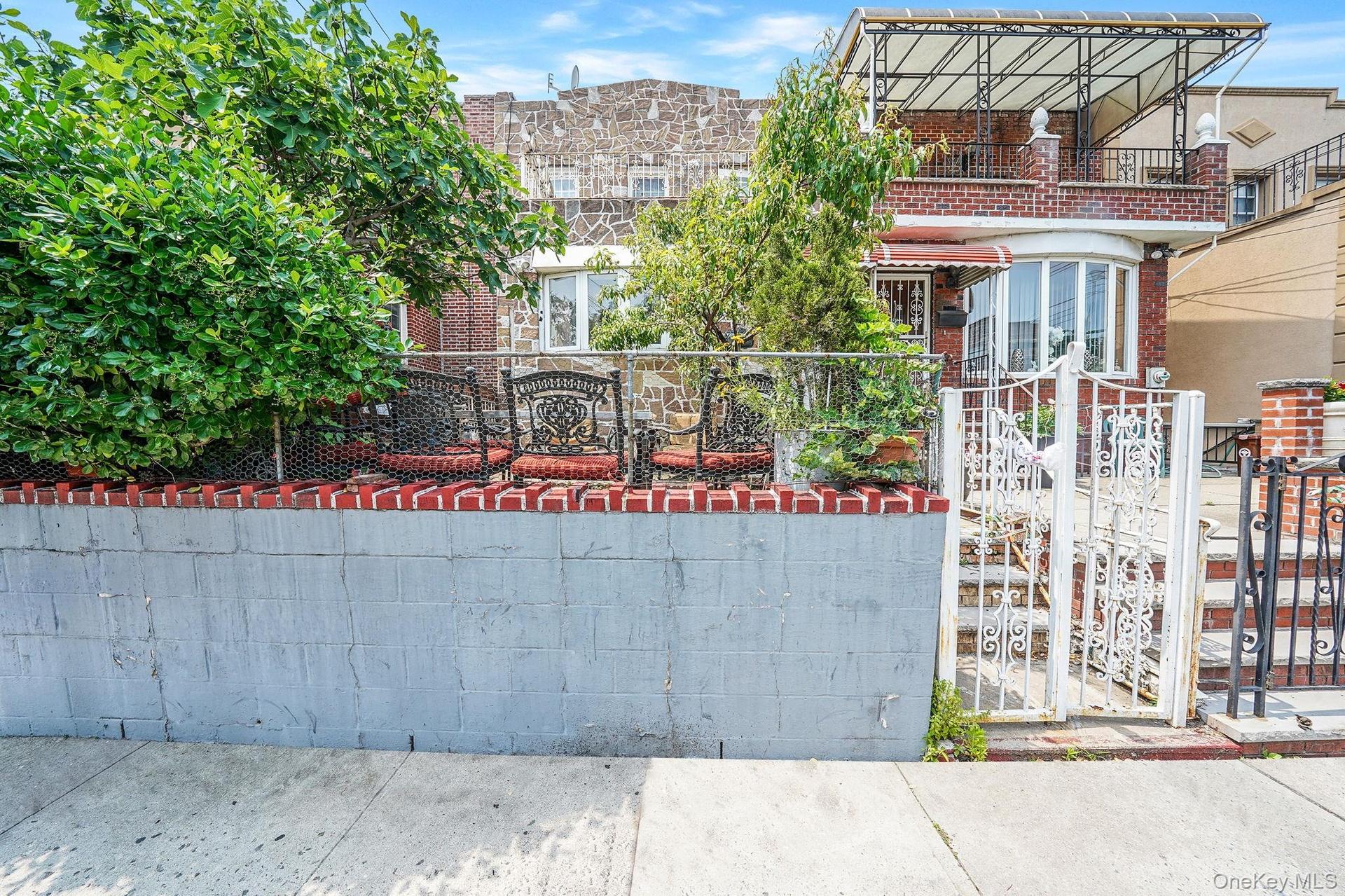 View of front of property with a gate, a balcony, and brick siding