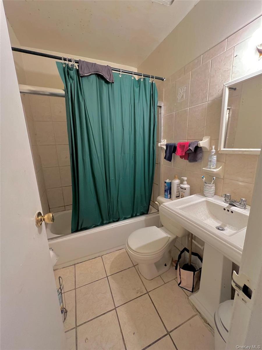 Full bathroom featuring toilet, shower / bath combination with curtain, tile walls, tile patterned flooring, and tasteful backsplash