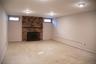 Large finished room with fireplace located in the basement level.