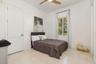 Light-filled guest bedroom featuring marble flooring, a modern ceiling fan, and a large window with outdoor landscaping visible