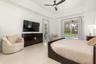 Spacious room featuring marble flooring, a tray ceiling with a dark-toned ceiling fan, and sliding glass doors opening to an exterior patio and pool a