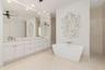 Spacious bathroom featuring a dual vanity with white cabinetry and light-toned countertops, a freestanding white soaking tub, and a glass-enclosed sho