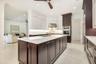 Gourmet kitchen featuring a large central island with integrated sink, two-tone cabinetry, built-in stainless steel appliances, and under-cabinet ligh