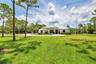 Expansive green lawn with mature pine trees framing a single-story residence
