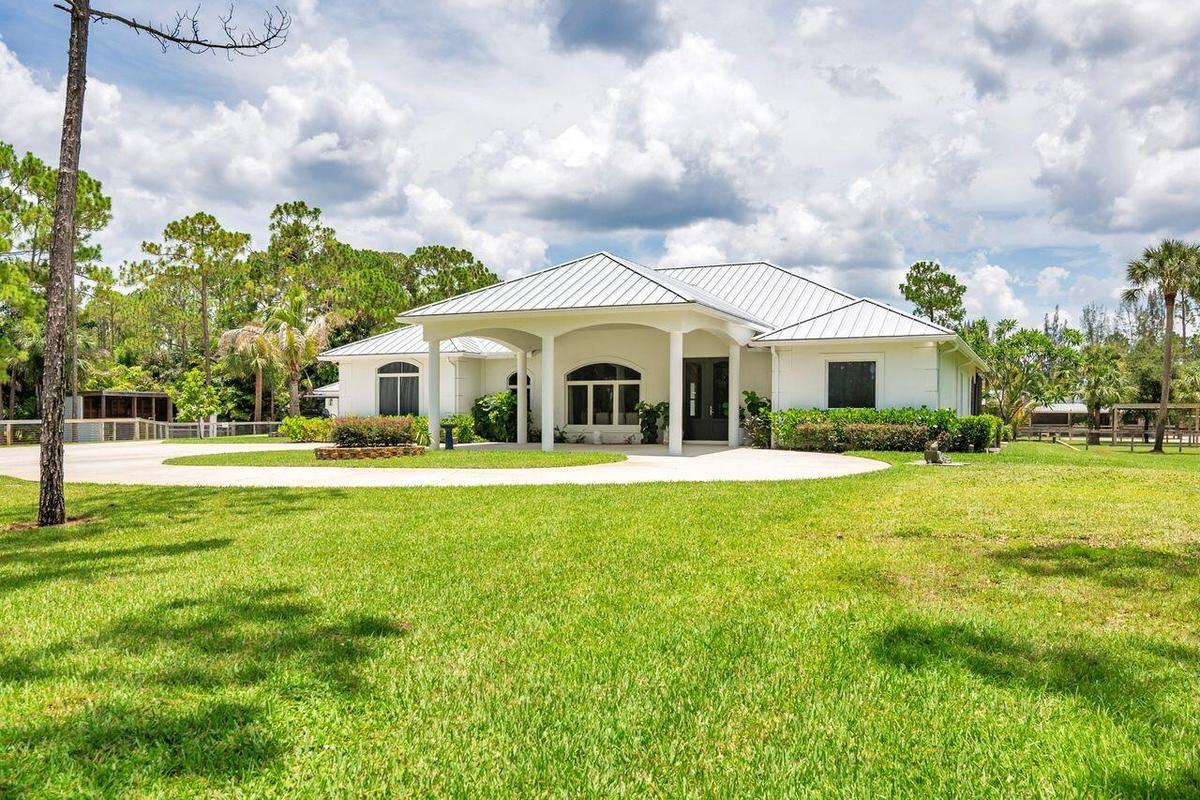 White stucco exterior with a metal roof and an arched portico entry