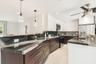Gourmet kitchen featuring dark wood cabinetry, white upper cabinets, stainless steel appliances, and contrasting dark countertops with a white vein pa