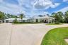 Expansive circular drive, portico, metal roof, and an attached three-car garage
