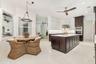 Modern kitchen featuring a large central island with a sink, white upper cabinetry, rich dark wood lower cabinetry, and built-in stainless steel appli