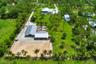 Expansive property featuring a main residence with a swimming pool, two metal-roofed outbuildings, a large equestrian arena, and mature trees with man
