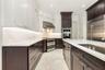Contemporary kitchen featuring white upper cabinetry, dark wood-finish lower cabinetry, and light countertops
