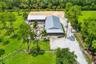 Expansive equestrian facility featuring two large structures with metal roofs and a sand arena